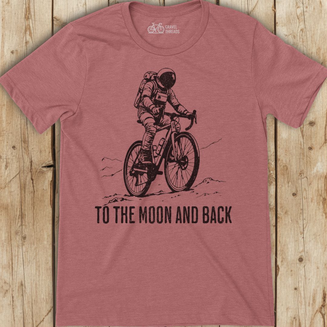 Red t-shirt with an astronaut on a bike graphic and 'To the Moon and Back' text on a wooden background