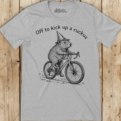 Gray t-shirt with a graphic of a beaver riding a bicycle and text on a wooden surface