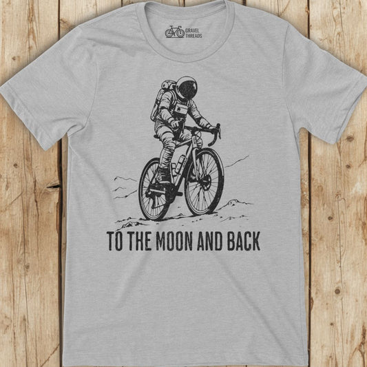 Gray t-shirt with an astronaut riding a bike graphic and 'To the Moon and Back' text on a wooden surface.