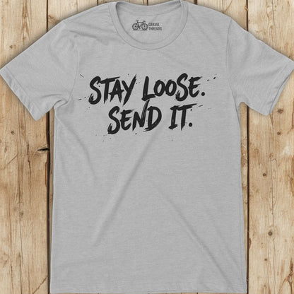 Gray t-shirt with 'Stay Loose. Send It.' text on a wooden surface