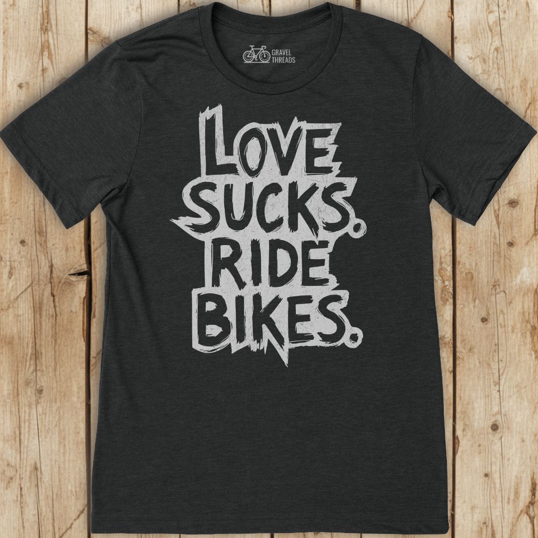 Black t-shirt with 'Love sucks, ride bikes' text on a wooden surface
