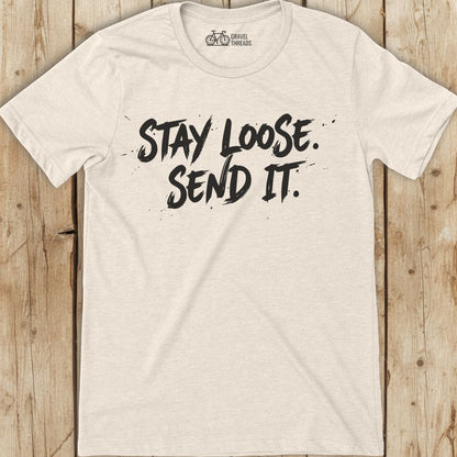 Beige t-shirt with 'Stay Loose. Send It.' text on a wooden surface