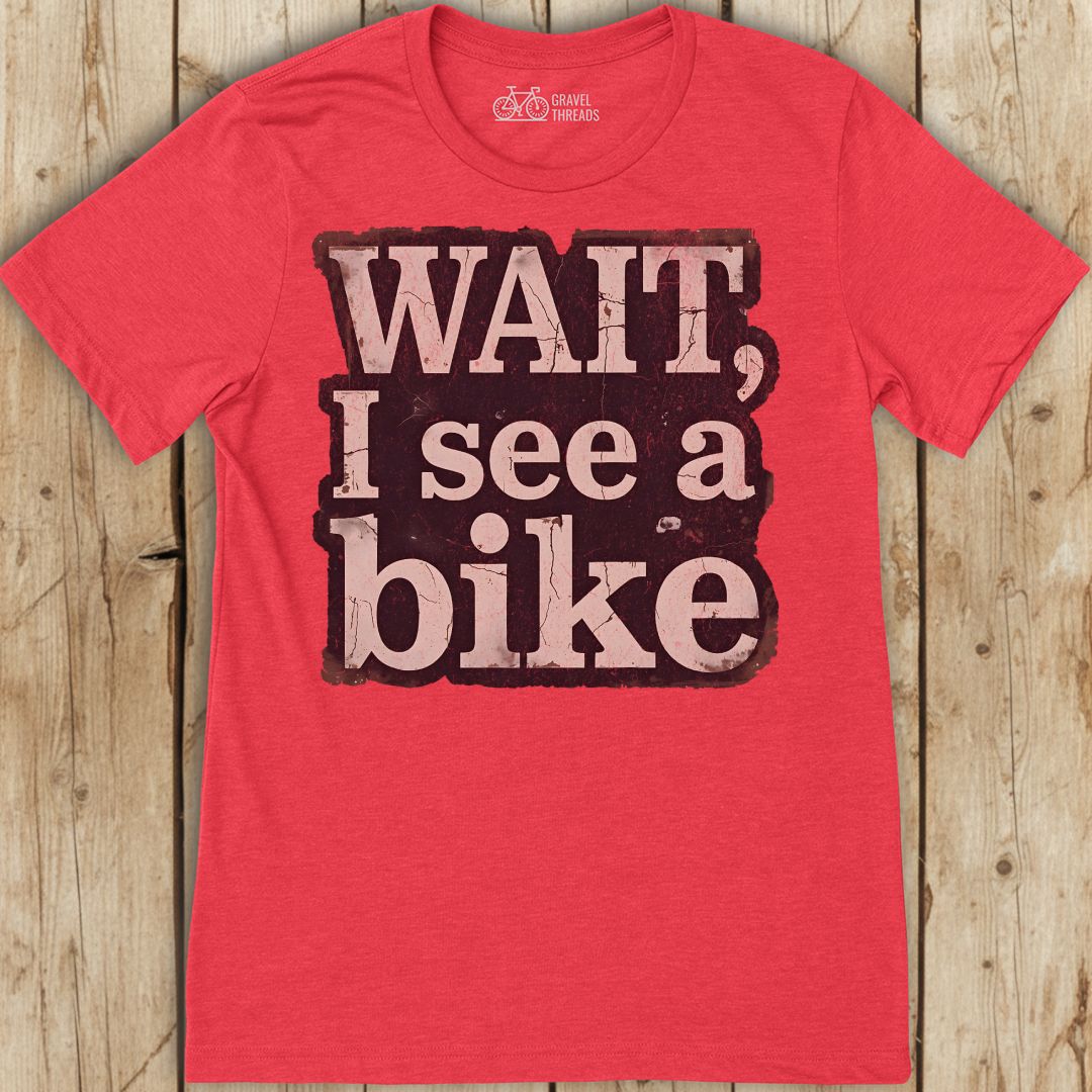 Red t-shirt with 'Wait, I see a bike' text on a wooden background