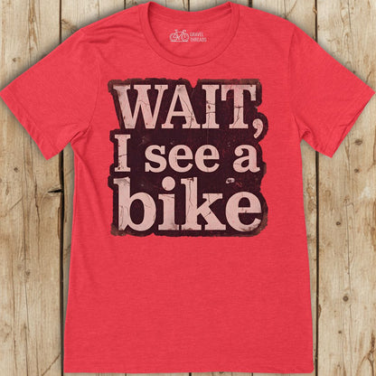 Red t-shirt with 'Wait, I see a bike' text on a wooden background