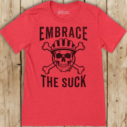 Red t-shirt with skull and crossbones graphic and text 'Embrace The Suck' on a wooden background