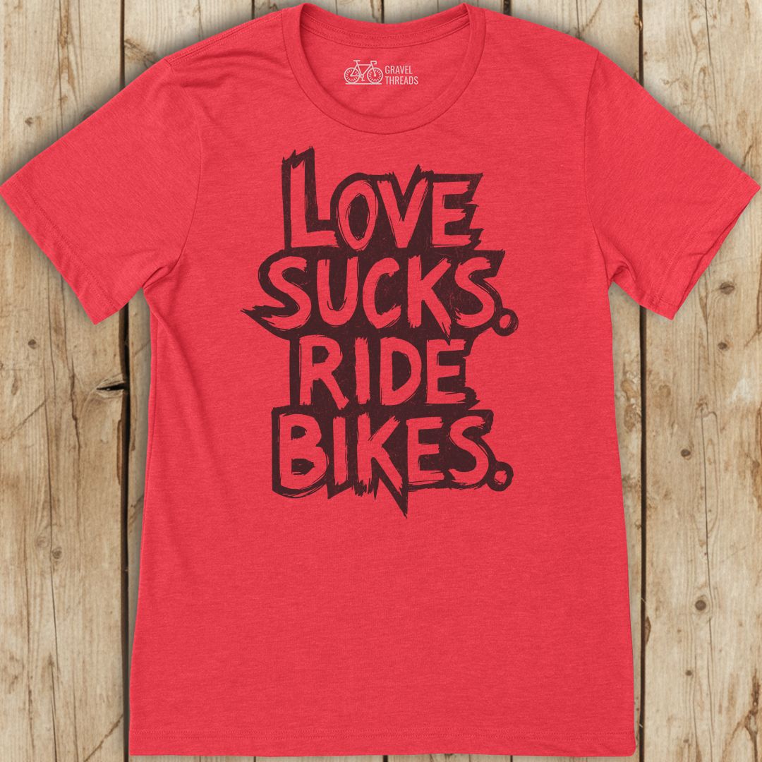 Red t-shirt with black text 'I LOVE SUCKS. RIDE BIKES.' on a wooden background