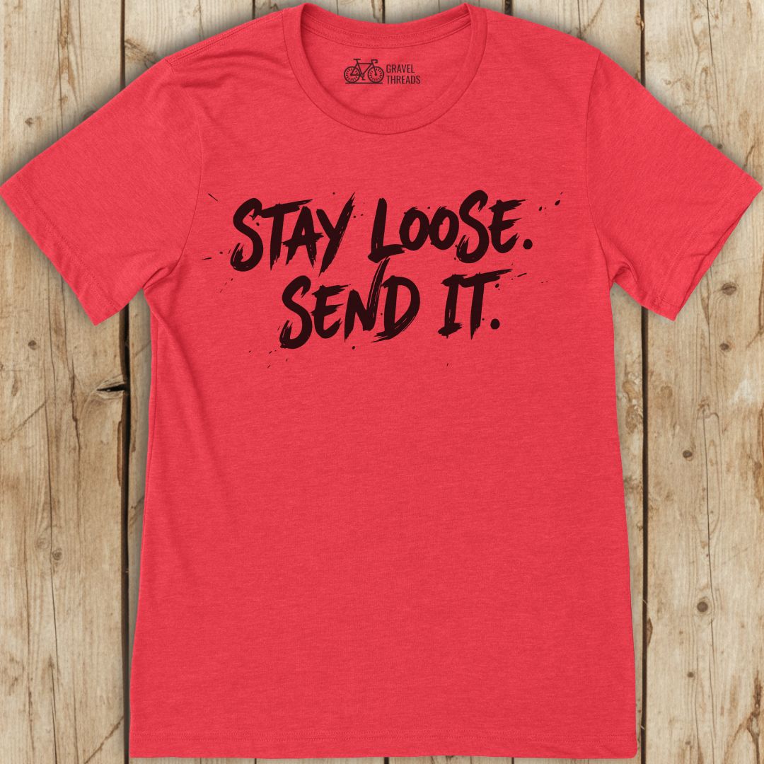 Red t-shirt with 'Stay Loose. Send It.' text on a wooden surface