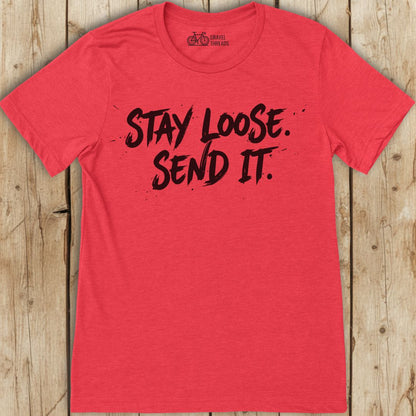 Red t-shirt with 'Stay Loose. Send It.' text on a wooden surface