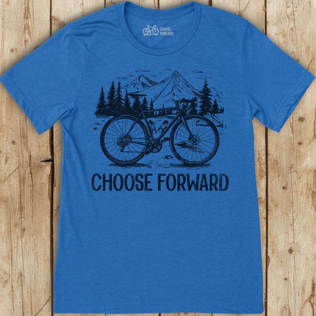 Blue t-shirt with bicycle graphic and 'Choose Forward' text on a wooden surface