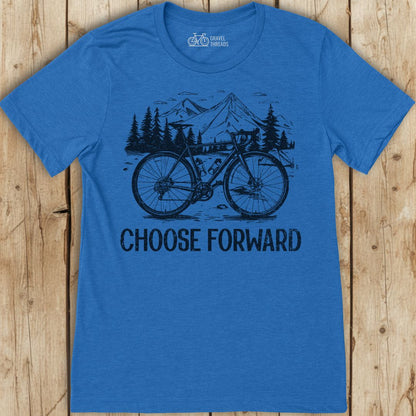 Blue t-shirt with bicycle graphic and 'Choose Forward' text on a wooden surface