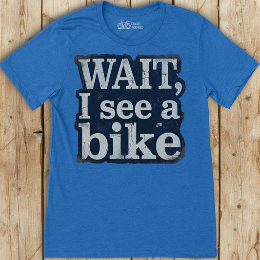 Blue t-shirt with 'WAIT, I see a bike' text on a wooden background